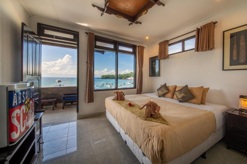 a bedroom with a large bed with a view of the ocean at Absolute Scuba Bali Dive Resort in Padangbai