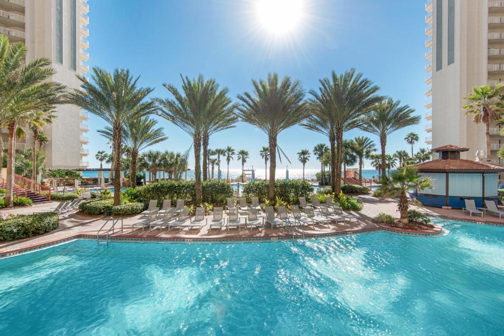 a pool with chairs and palm trees in a resort at Shores of Panama III in Panama City Beach