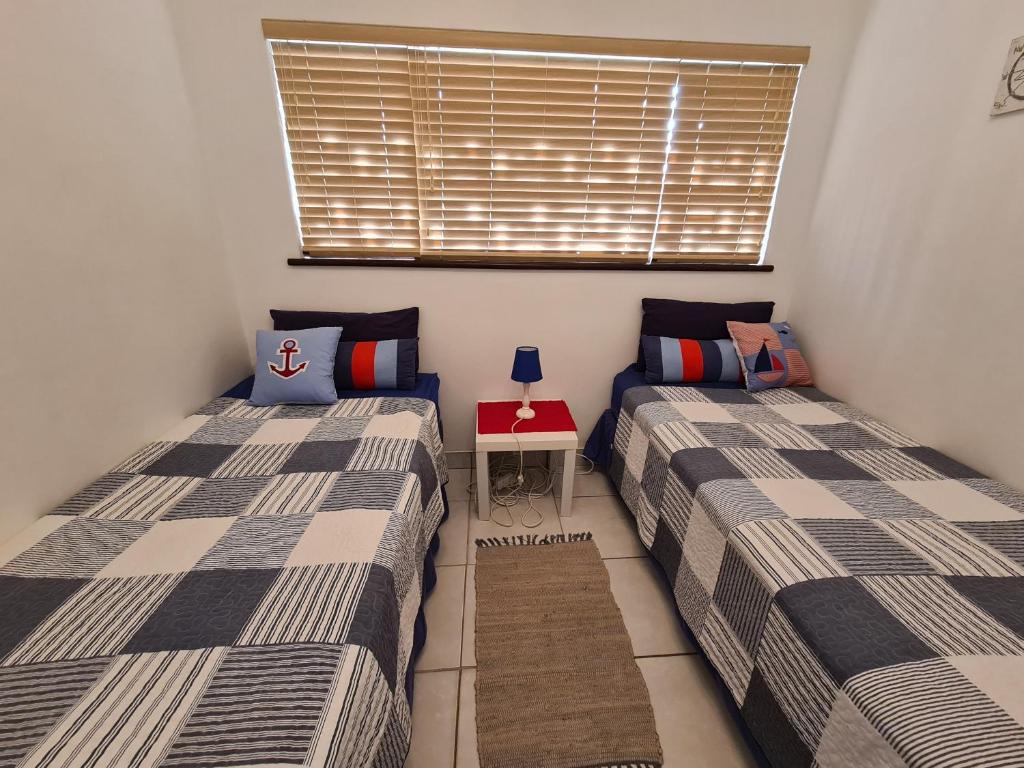 two beds in a small room with a window at Rockview Holiday Beach Apartment in Hibberdene