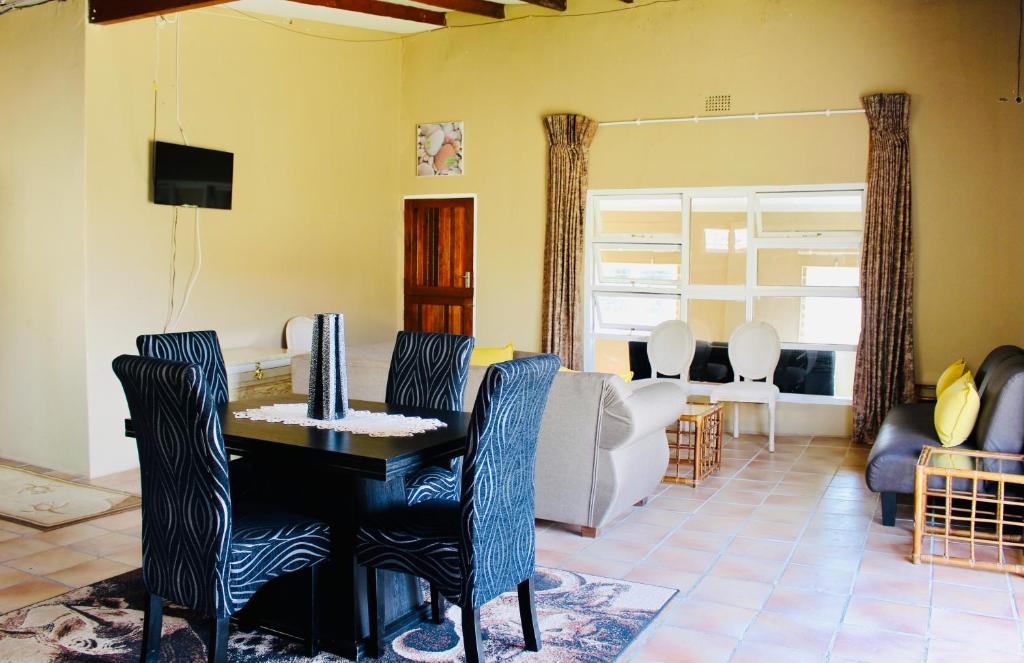 een woonkamer met een tafel en stoelen en een bank bij Coffee Bay Lodge in Coffee Bay
