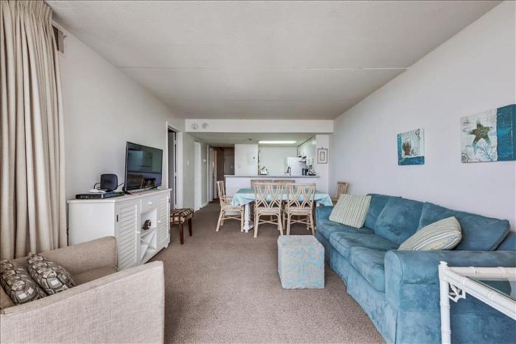 un soggiorno con divano blu e una sala da pranzo di Sea Watch Condos III a Ocean City