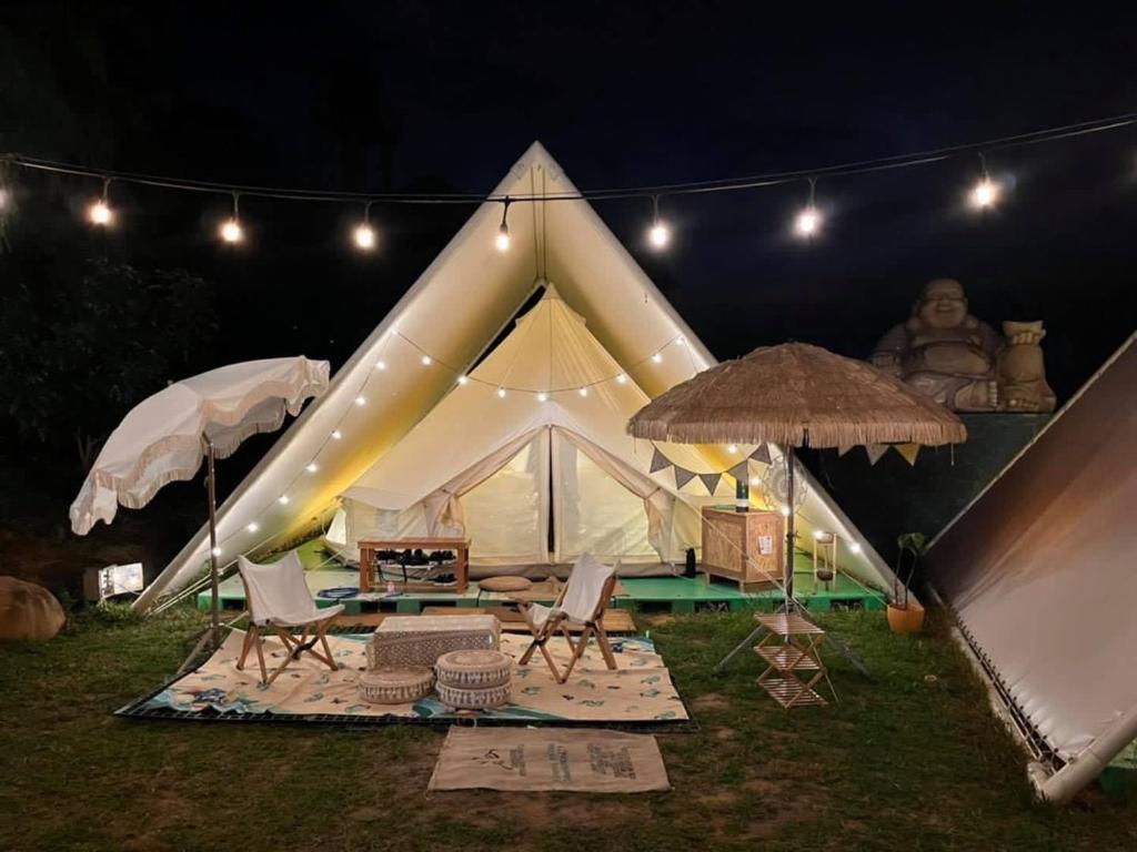 桃園區的住宿－晃晃印地安帳棚露營區，大型白色帐篷,晚上配有椅子和遮阳伞