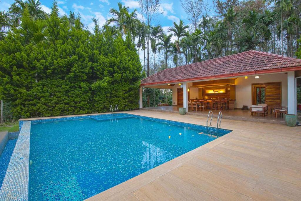 a swimming pool in front of a house at StayVista at Tall Silver with Infinity Pool & Breakast in Madikeri