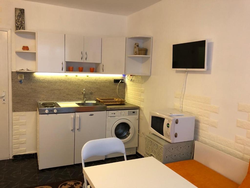 eine Küche mit einer Waschmaschine und einer Mikrowelle in der Unterkunft Боксониера Georgi Georgiev in Warna