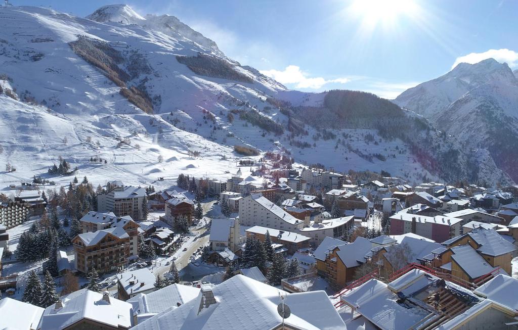 une ville couverte de neige avec des montagnes en arrière-plan dans l'établissement Odalys Chalet Chambertin Lodge, à Les Deux Alpes