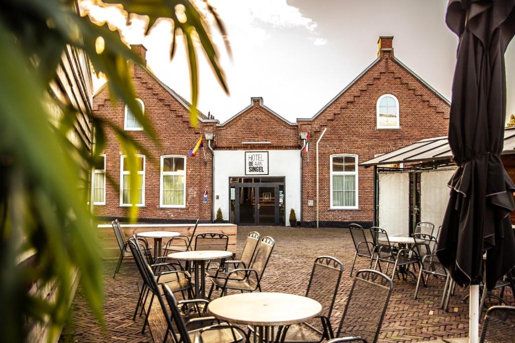 eine Gruppe von Tischen und Stühlen vor einem Gebäude in der Unterkunft Hotel Aan De Singel in Delfzijl