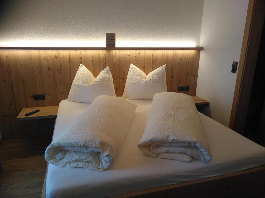 Una cama con almohadas blancas y toallas. en Ferienwohnung Alpenluft, en Hochfilzen