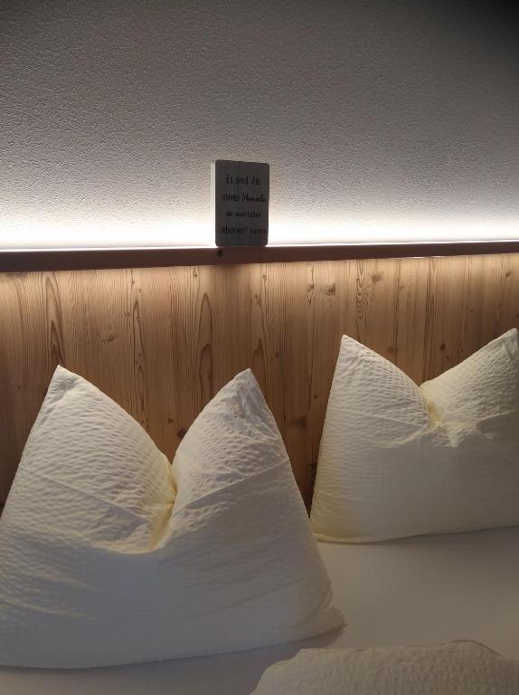 a bed with white pillows with a sign on it at Ferienwohnung Alpenluft in Hochfilzen
