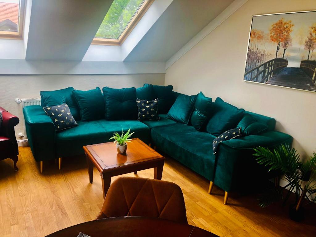 uma sala de estar com um sofá verde e uma mesa em Birdland Apartman em Bük