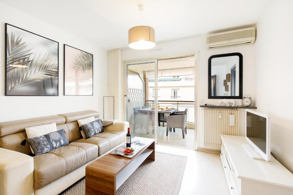 een woonkamer met een bank en een tafel bij Le Charme YourHostHelper in Cannes
