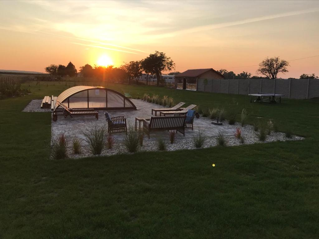 a sunset in a field with benches and a pond at U Jeřába - komplex C in Horní Věstonice