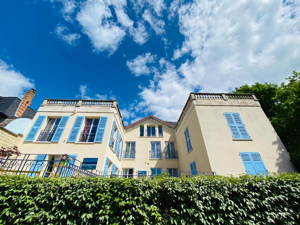 two white buildings with blue windows and a hedge at Villa Talisman in Saint-Germain-en-Laye