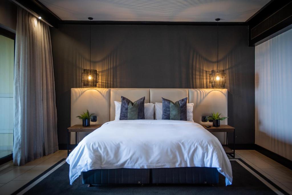 a bedroom with a large white bed with two tables at The Capital Zimbali in Ballito