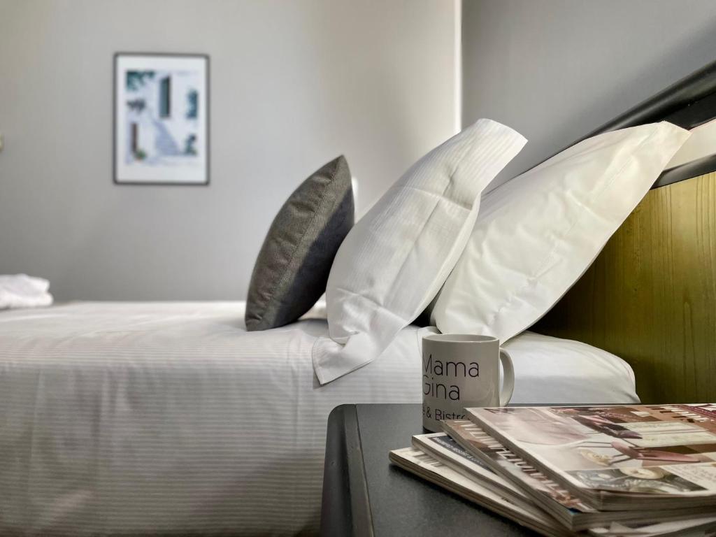 a bed with pillows and a table with a coffee mug at Hotel Gardenia Fiera in Cermenate