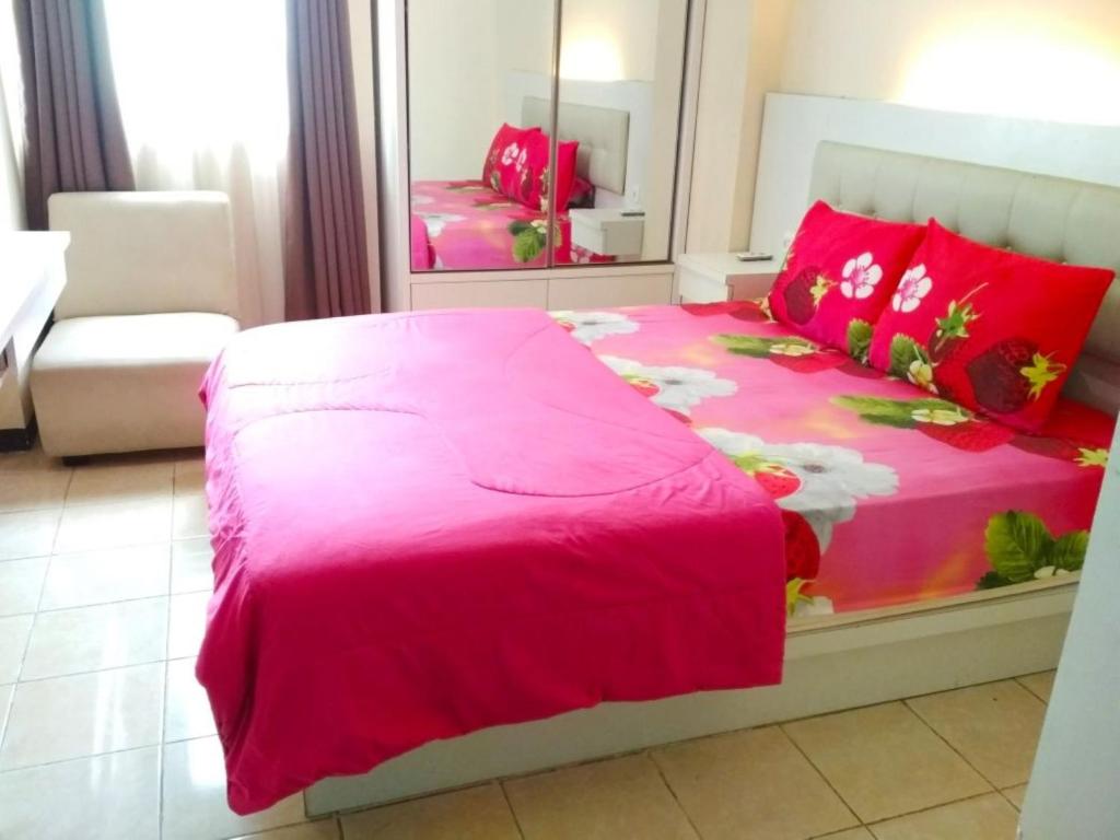 ein Schlafzimmer mit einem rosa Bett und einem Spiegel in der Unterkunft The Suites Metro by Faris Property in Bandung