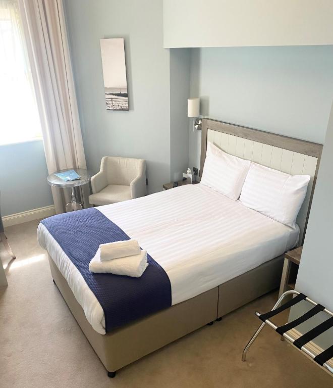 a bedroom with a large bed and a chair at Yarrow Hotel in Broadstairs