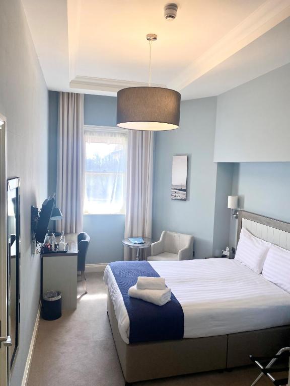 a bedroom with a bed with a blue wall at Yarrow Hotel in Broadstairs