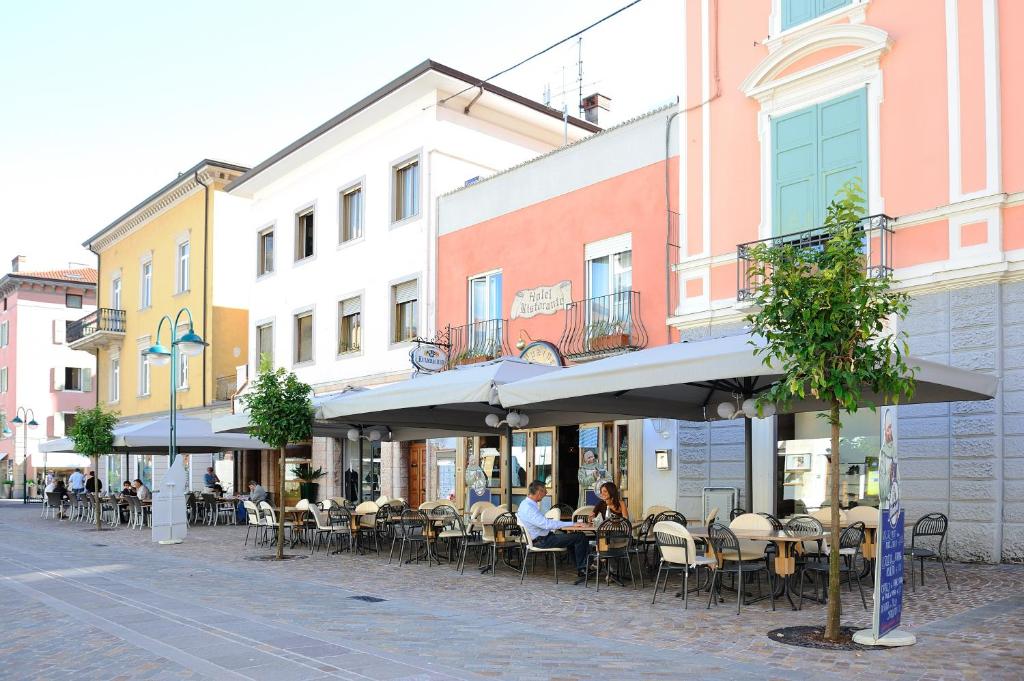 a group of people sitting at tables on a street at Hotel Vittoria in Riva del Garda