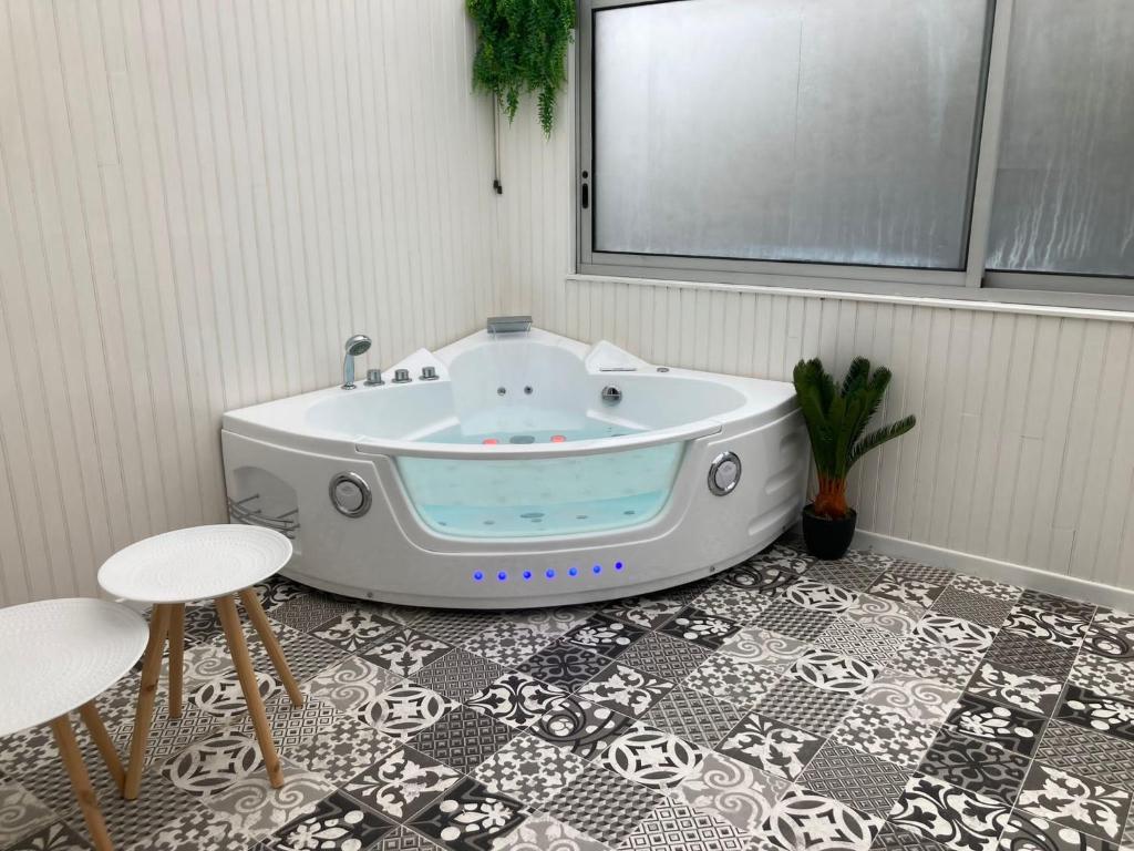 eine Badewanne in einem Zimmer mit einem Tisch und 2 Hockern in der Unterkunft NG SuiteHome - Lanester Lorient - Balnéo - Netflix - Wifi in Lanester