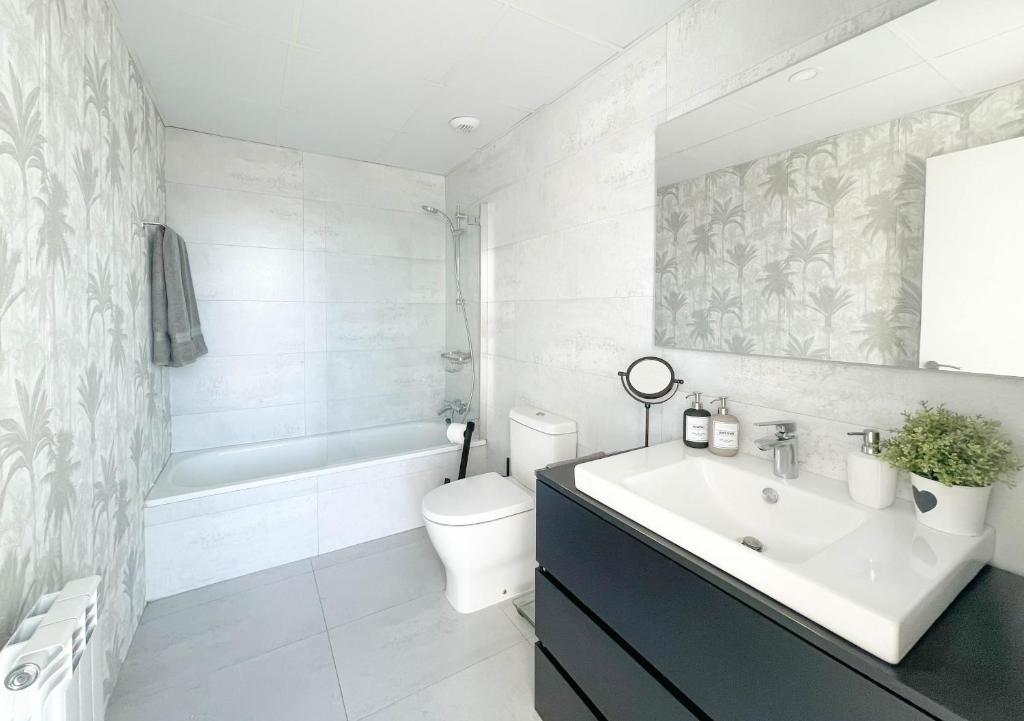 un bagno bianco con lavandino e WC di Ático mejores vistas al Pilar jacuzzi y garaje a Saragozza