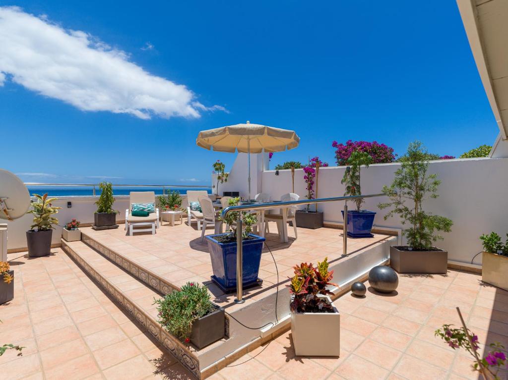 un patio con sombrilla, sillas y plantas en Casa LEX, en Playa del Inglés