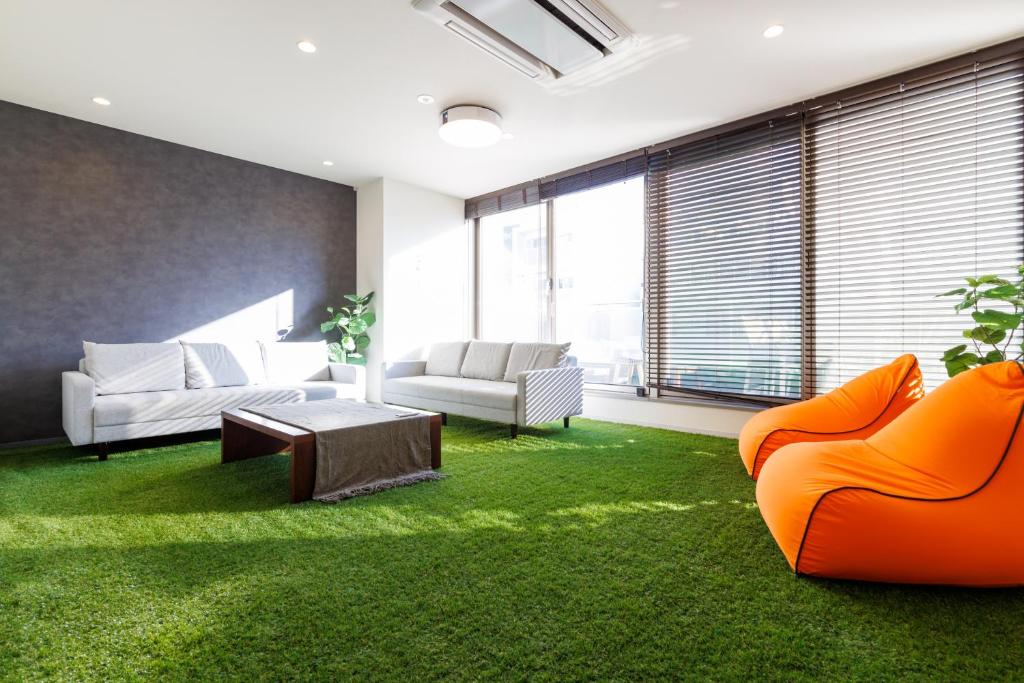 a living room with orange furniture and green carpet at STAY & GO Shinsaibashi-Kita in Osaka