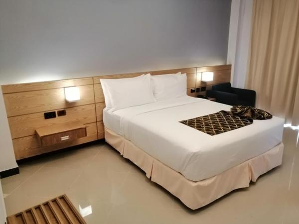 um quarto com uma grande cama branca e uma cadeira em Mazeki Addis Boutique Hotel em Addis Ababa