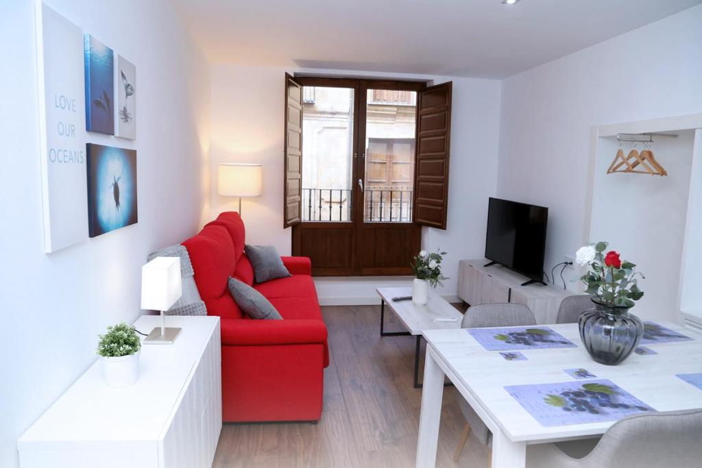 a living room with a red couch and a table at Apto Turístico Plaza del Mercado 1.2 in Salamanca