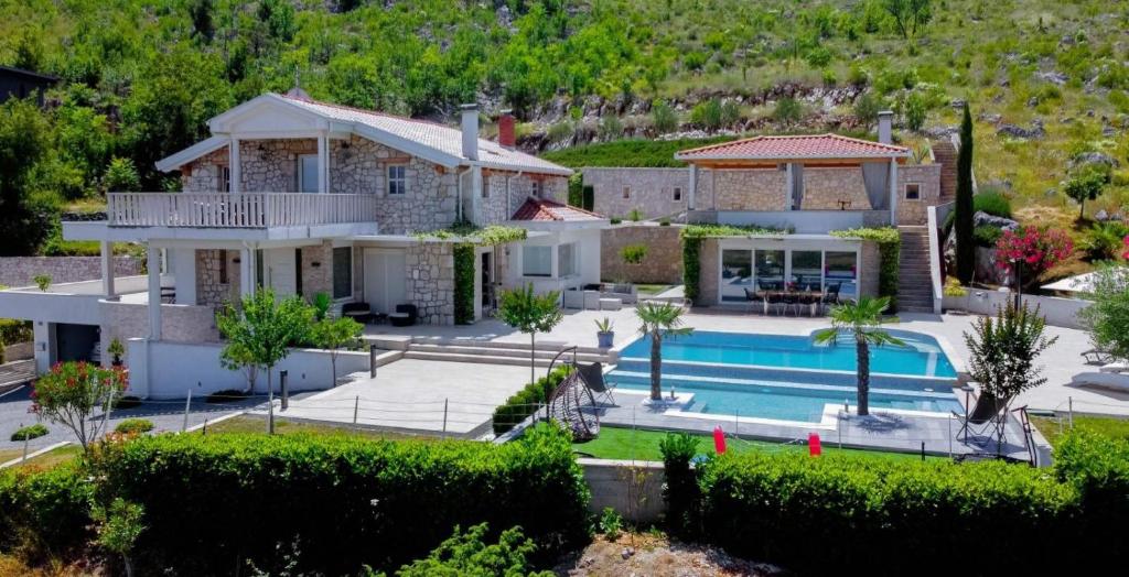 eine Villa mit einem Pool und einem Haus in der Unterkunft Villa VAND Paradiso in Međugorje
