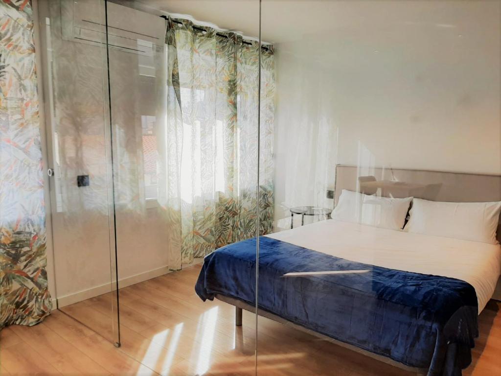 1 dormitorio con 1 cama y pared de cristal en Apartamentos Celestina by gaiarooms, en Salamanca