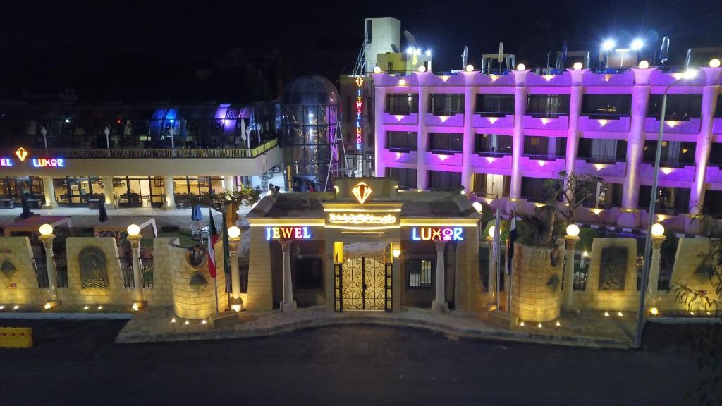 Jewel Luxor Hotel في الأقصر: مبنى كبير أمامه أضواء أرجوانية