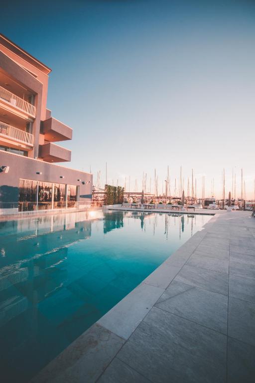a large swimming pool next to a building with boats at Mosella Suite Hotel in Sottomarina