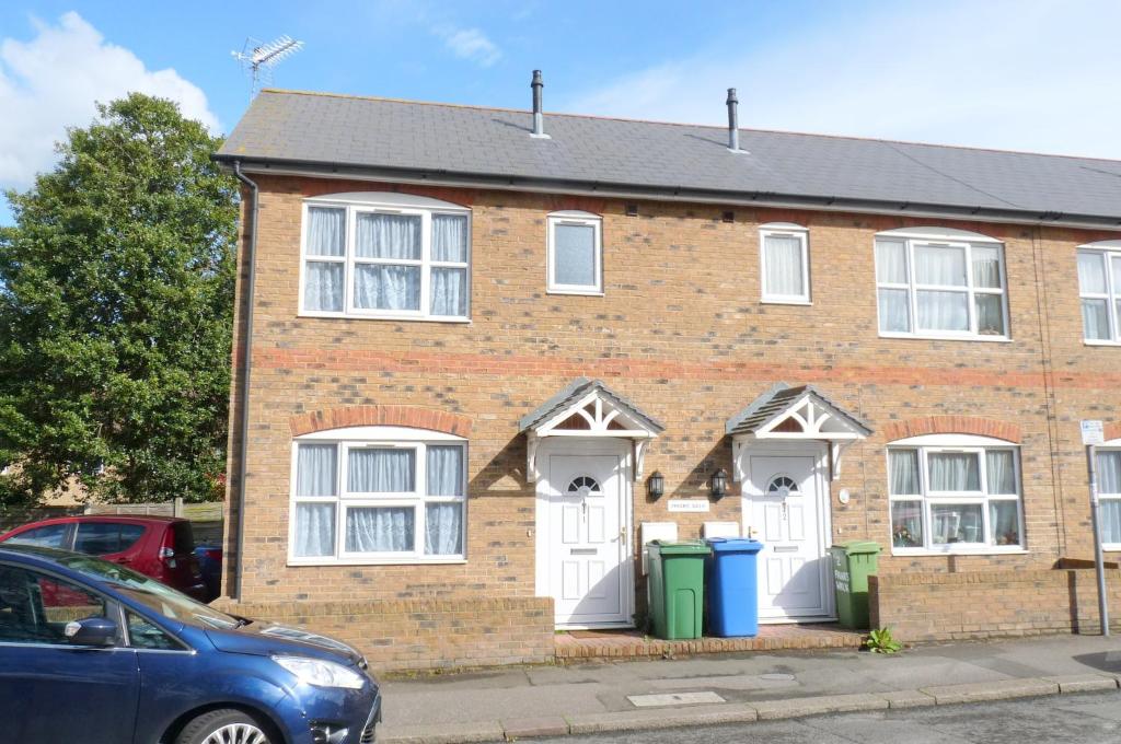 una casa de ladrillo con dos puertas blancas y dos cubos de basura en Friars Walk 2 with 2 bedrooms, 2 bathrooms, fast Wi-Fi and private parking, en Sittingbourne