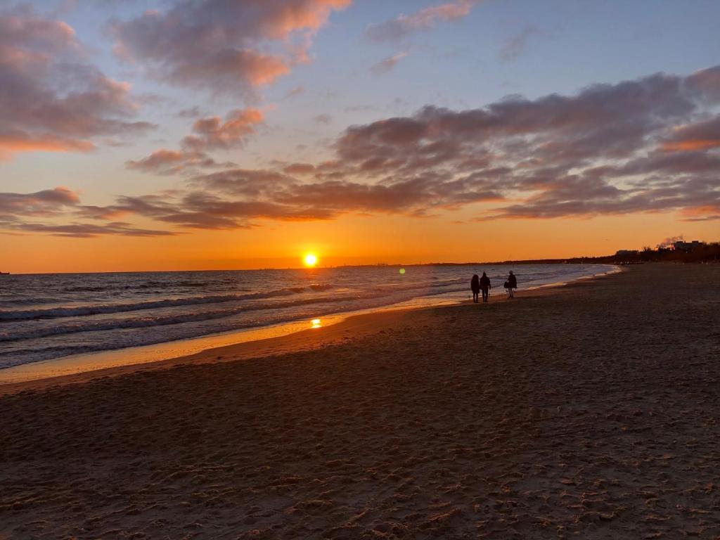 two people walking on the beach at sunset at Sopot 34 przy plaży in Sopot