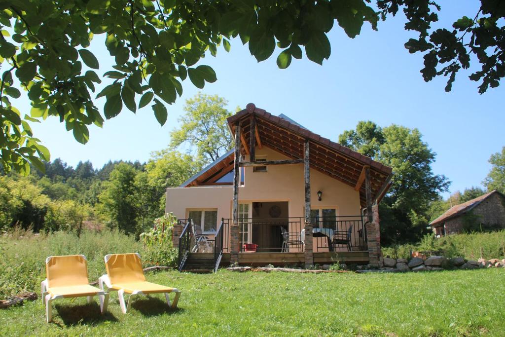 een huis met twee stoelen in het gras bij Gite L'Ane Qui Rit in Le Breuil
