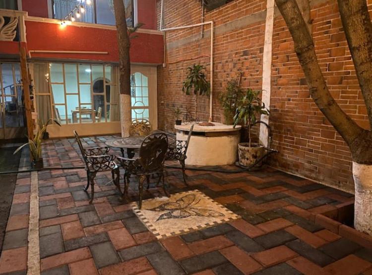 d'une terrasse avec une table, des chaises et un mur en briques. dans l'établissement Departamento Magnolia, 5 min AEROPUERTO, à Nextetelco