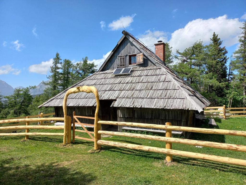 une ancienne grange avec une clôture en bois devant elle dans l'établissement Velika Planina - Chalet Rušovc - Location with fully privacy, à Stahovica