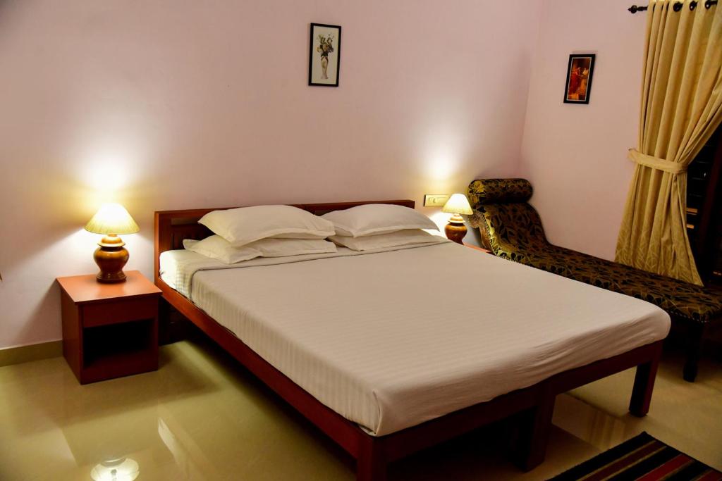 ein Schlafzimmer mit einem Bett, einem Stuhl und zwei Lampen in der Unterkunft Thanal Homestay in Ernakulam