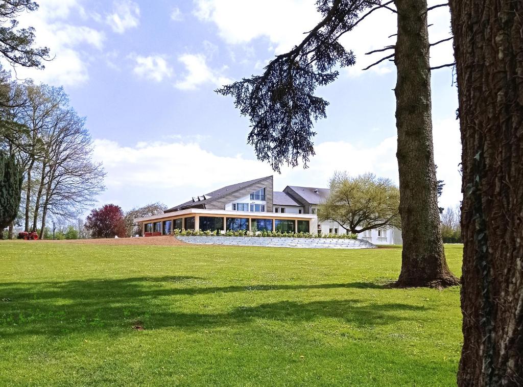 a house in a field with a tree at Hôtel le Corbusson in Saint-Berthevin