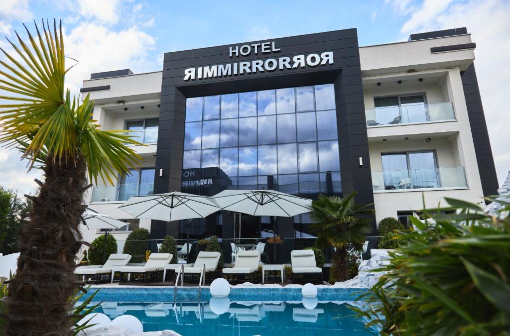 a hotel with a swimming pool in front of a building at Hotel Mirror in Skopje