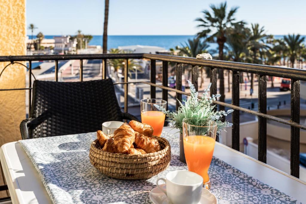 einen Tisch mit einem Korb mit Gebäck und Orangensaft auf einem Balkon in der Unterkunft Sur Suites Perla 6-4 in Fuengirola