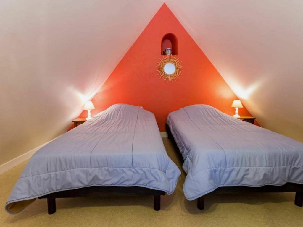 2 Betten in einem Zimmer mit roter Wand in der Unterkunft Gîte Saint-Lyphard, 3 pièces, 4 personnes - FR-1-306-1132 in Saint-Lyphard