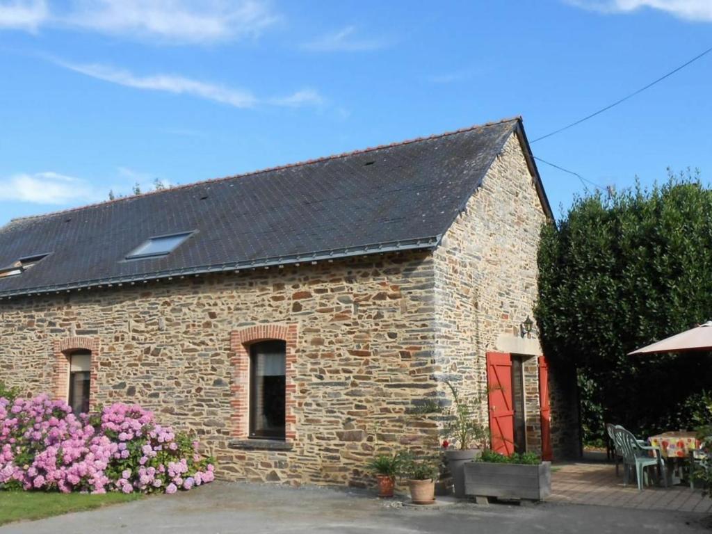 a stone building with a red door and pink flowers at Gîte Guémené-Penfao, 4 pièces, 7 personnes - FR-1-306-1130 in Guéméné-Penfao