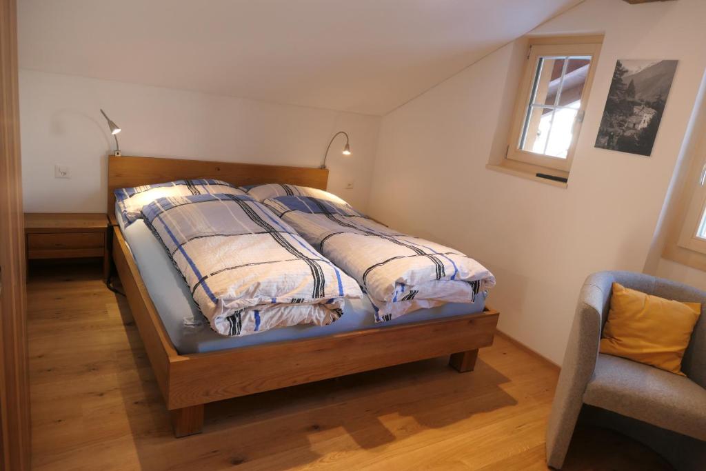 a bedroom with a bed and a chair and a window at Chalet Valeria in Saas-Fee