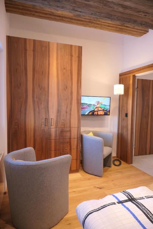 a bedroom with a bed and two chairs and a tv at Chalet Valeria in Saas-Fee