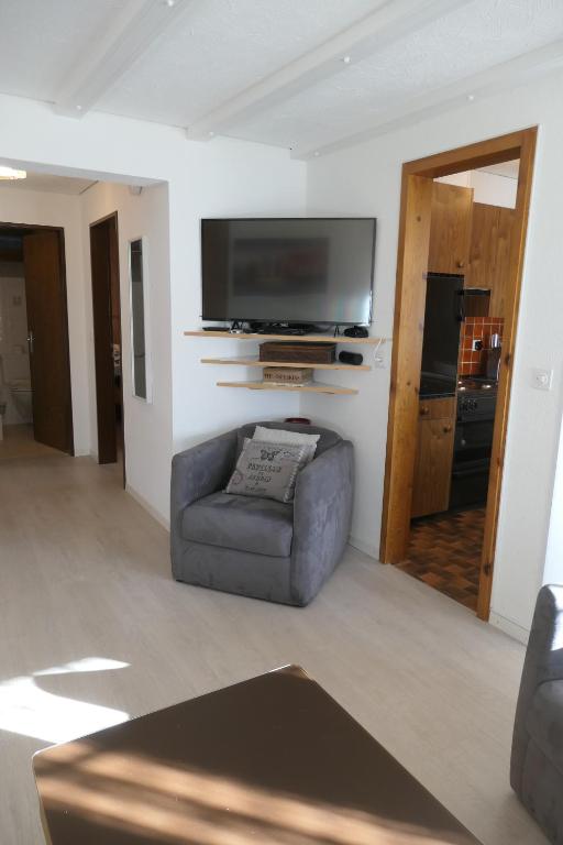 a living room with a chair and a flat screen tv at Chalet Valeria in Saas-Fee