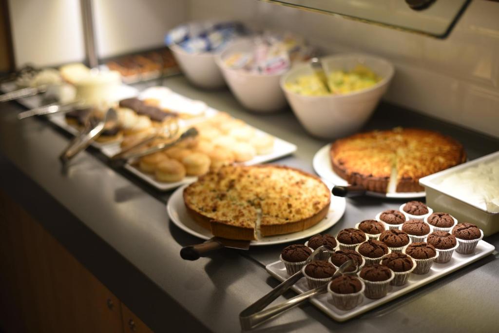 a counter with several different types of cakes and pastries at Holiday Inn Express - Paris - CDG Airport by IHG in Roissy-en-France
