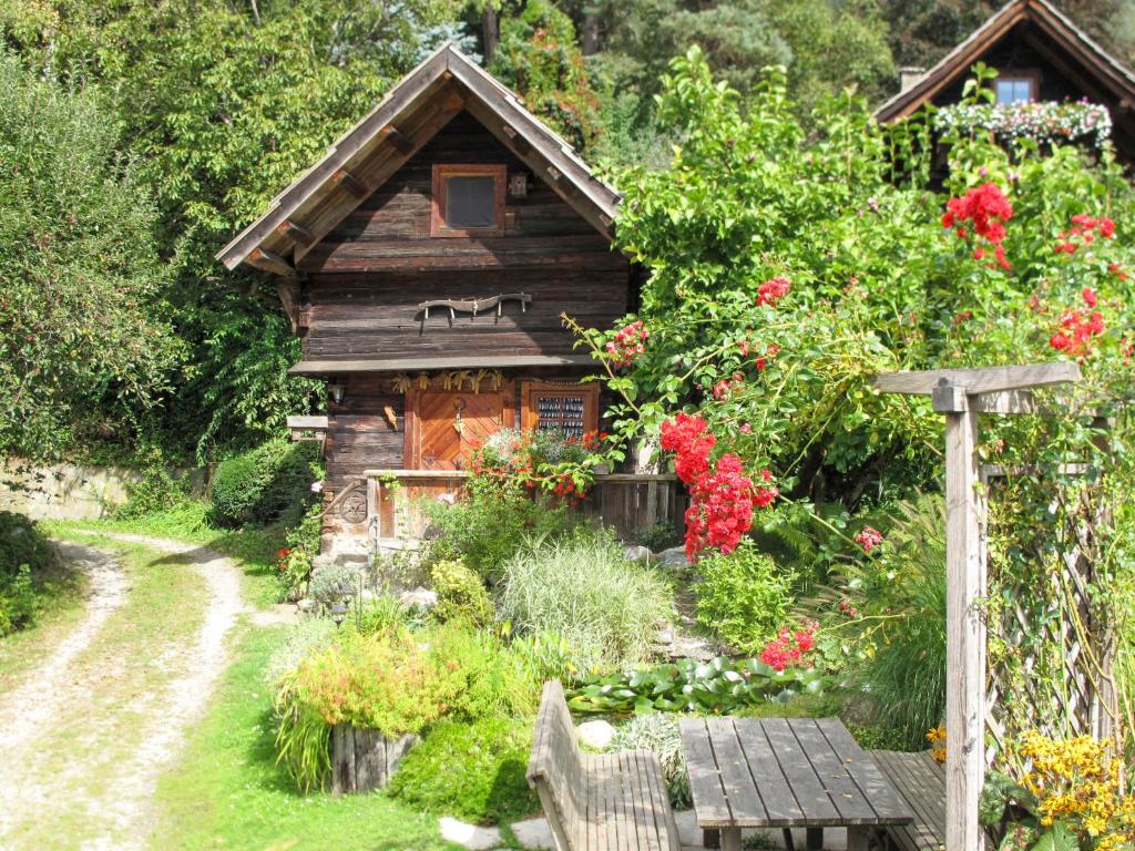 een houten hut met bloemen en een bank ervoor bij Holiday Home Kunzhof - TFN110 by Interhome in Winklern