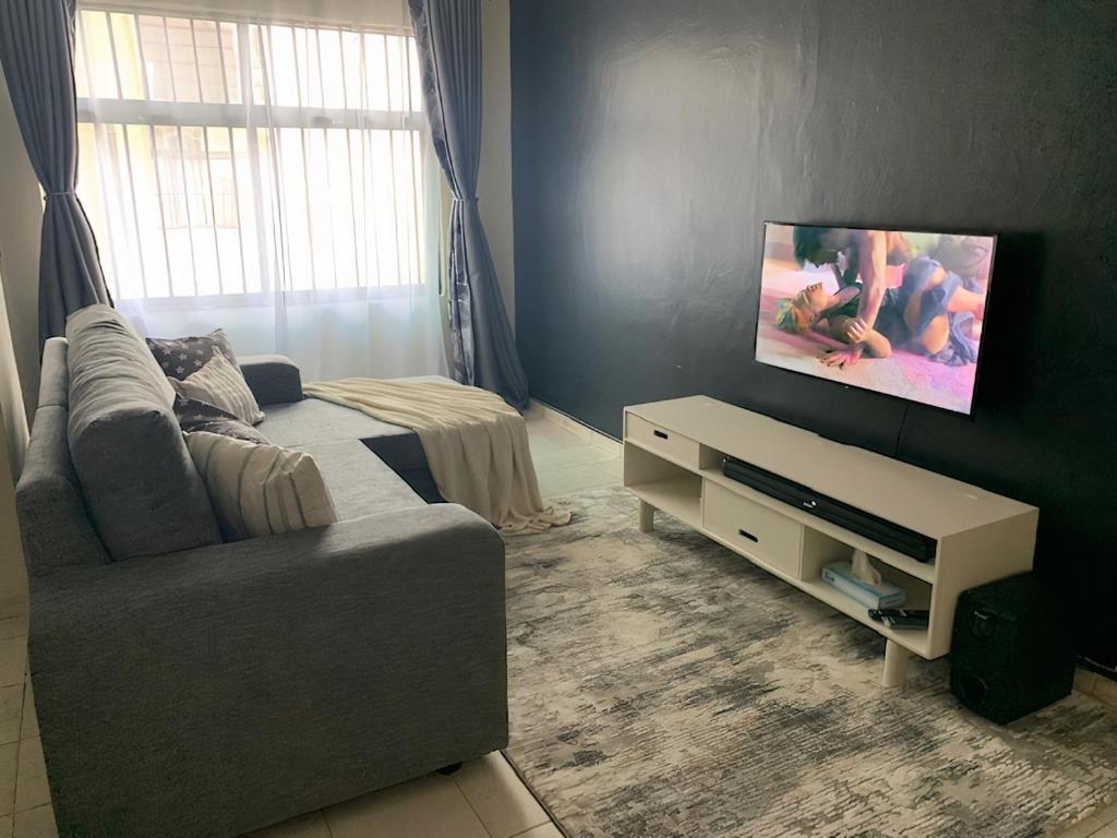 Una sala de estar con un sofá y un televisor de pantalla plana. en Peaceful and Lovely 1 bedroom with a city view., en Nairobi