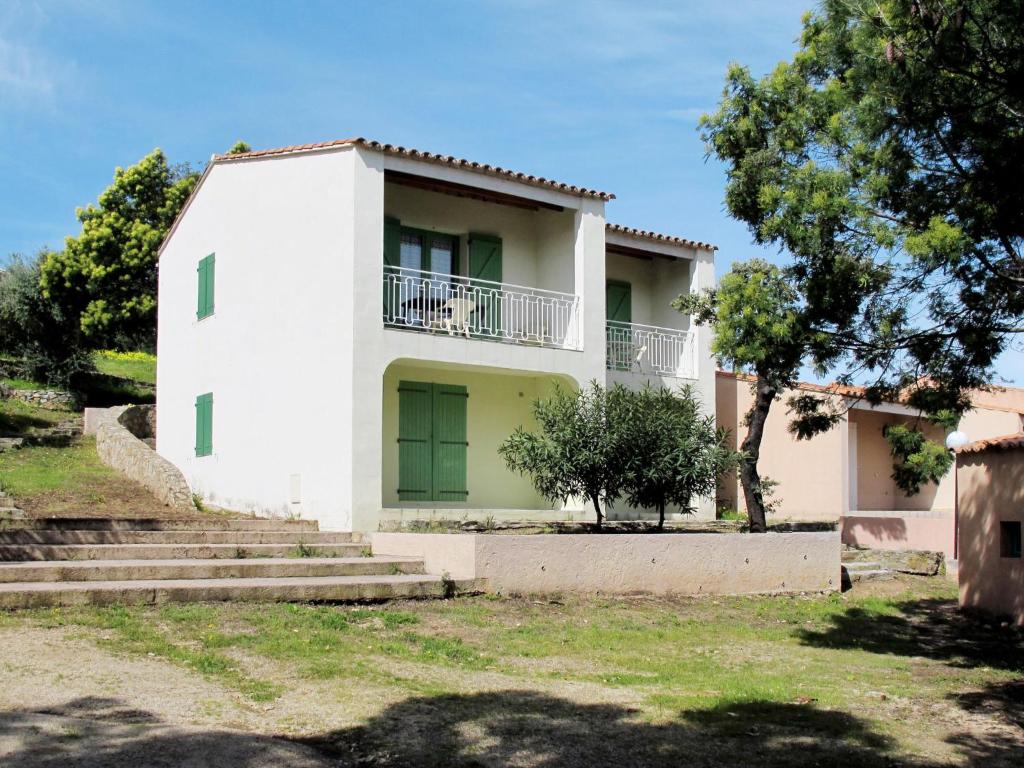 una casa blanca con un árbol y escaleras en Apartment Cala di Sole - ALG131 by Interhome en Algajola